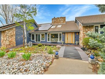 Inviting home with stone accents, wood trim, and solar panels on a sunny day at 1 Red Fox Ln, Littleton, CO 80127