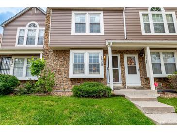 A townhome featuring a stone and vinyl exterior, a well-manicured lawn, and a cozy front porch at 4636 S Dillon Ct # B, Aurora, CO 80015