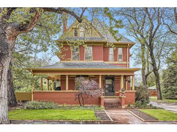 Stunning red brick two-story home featuring a covered front porch, landscaped yard, and charming architectural details at 835 Niagara St, Denver, CO 80220