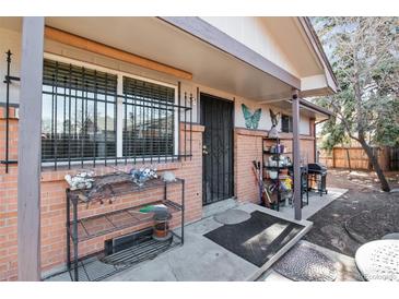 Charming front porch with secure window bars and a decorative butterfly accent on the brick exterior at 4942 W 9Th Ave, Denver, CO 80204