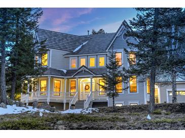 Stunning two-story home featuring a welcoming front porch and beautiful architectural details at 6857 Timbers Drive, Evergreen, CO 80439