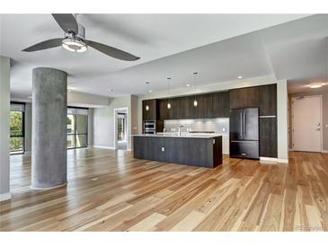Bright living room featuring wood floors, a concrete pillar, and an open layout to a modern kitchen at 4200 W 17Th Ave # 235, Denver, CO 80204
