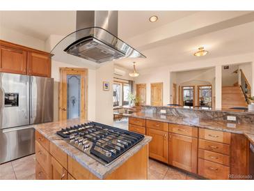 An open kitchen featuring stainless steel appliances and a central island with a gas cooktop and a modern range hood at 2673 S Cook St, Denver, CO 80210