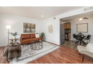 Cozy living room with a brown leather sofa, area rug, and access to the kitchen and dining area at 5300 E Cherry Creek South Dr # 1327, Denver, CO 80246