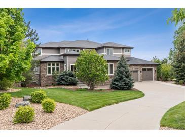 Elegant two-story home boasts a three-car garage, manicured lawn, and a charming stone and siding facade at 5334 Sedona Dr, Parker, CO 80134