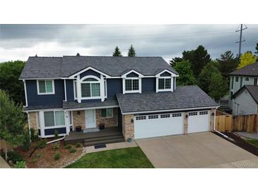 Charming two-story home featuring a three-car garage, blue siding, and brick accents, situated on a well-manicured lawn at 7404 La Quinta Ln, Lone Tree, CO 80124