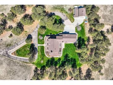 Stunning aerial view of estate home and detached garage surrounded by mature trees on a well-manicured lawn at 38666 County Road 21, Elizabeth, CO 80107