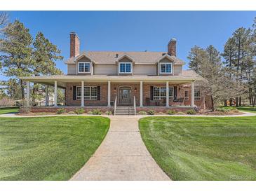 Charming brick home featuring a welcoming front porch, well-manicured lawn, and classic architectural details at 38666 County Road 21, Elizabeth, CO 80107