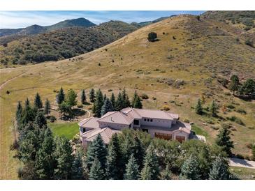 Luxury home with a terracotta tile roof surrounded by evergreen trees and grassy hillsides at 6634 Window Rock Ln, Morrison, CO 80465