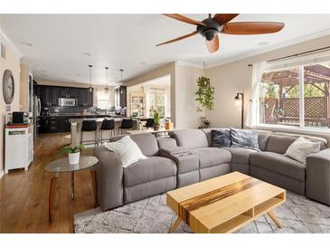 Open-concept living room boasts a ceiling fan, comfortable seating, and seamless flow to the kitchen, perfect for modern living at 3472 Harvard Pl, Broomfield, CO 80023