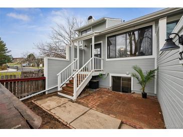 Gray townhome features a cozy brick patio and wooden steps with white railing leading to the front entrance at 378 Owl Dr, Louisville, CO 80027