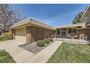 Charming brick home featuring a spacious front patio, lush lawn, and attached two-car garage at 32 Eagle Dr, Littleton, CO 80123