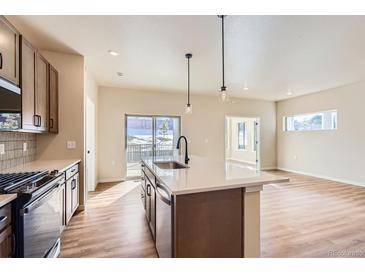 Modern kitchen features island, stainless steel appliances, and access to backyard patio at 804 W 128Th Pl, Westminster, CO 80234