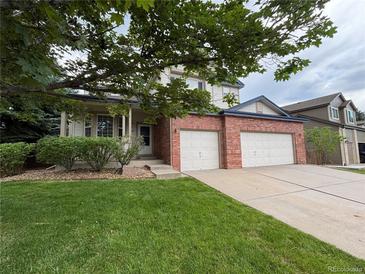 Charming two-story home featuring a brick facade, two-car garage, and well-maintained lawn and shrubbery at 10027 Sylvestor Rd, Highlands Ranch, CO 80129
