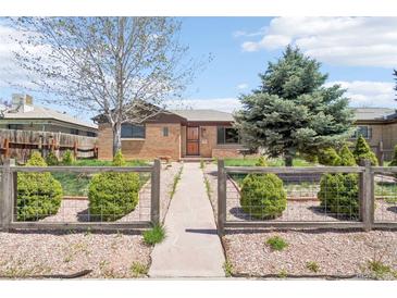 Charming brick home featuring a fenced yard with lush greenery, mature trees, and inviting pathway at 3580 Locust St, Denver, CO 80207
