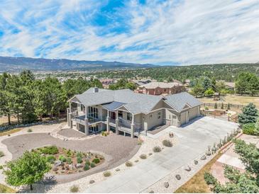 Stunning aerial view of a modern home with lush landscaping and a mountain backdrop, offering privacy and curb appeal at 670 Portland Rd, Monument, CO 80132