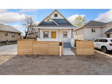 Charming home featuring a yellow front door, and a stylish wooden fence in front of the yard at 5123 Milwaukee St, Denver, CO 80216