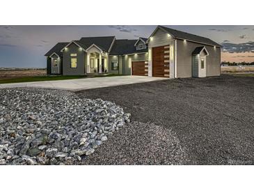 Stunning home exterior with modern garage doors, professional landscaping, and beautiful architectural lighting at 29780 E 162Nd Ave, Brighton, CO 80603
