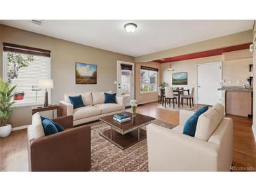 Bright living room featuring neutral walls, hardwood floors, and a view into the dining area at 20535 E 47Th Ave, Denver, CO 80249