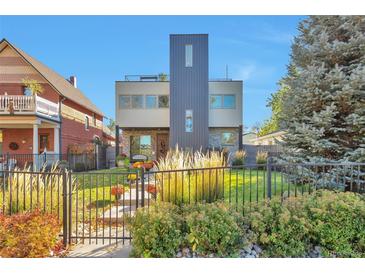 Modern two-story home with unique architecture, lush landscaping, and black iron fencing at 4514 W 34Th Ave, Denver, CO 80212