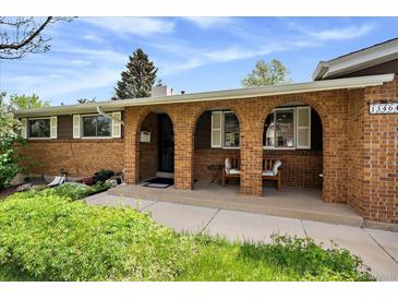 Charming brick home featuring an inviting front porch with arched openings and bench seating at 13464 W Virginia Dr, Lakewood, CO 80228