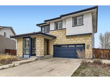 Two-story home with stone and siding, complemented by a blue garage door and trim at 10910 Touchstone Loop, Parker, CO 80134