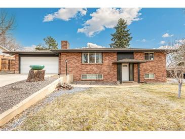 Charming brick home featuring an attached garage and mature landscaping at 6614 Everett St, Arvada, CO 80004