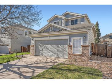 Two-story home with gray siding, brick accents, and a two-car garage, set against a clear blue sky at 20521 E Bellewood Pl, Aurora, CO 80015