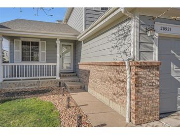 Charming home exterior with inviting front porch, brick accents and well maintained lawn and landscaping at 20521 E Bellewood Pl, Aurora, CO 80015