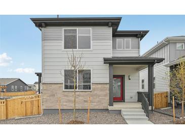 Two-story home with light gray siding, stone accents, a red door and a covered front porch at 6225 N Nepal Ct, Aurora, CO 80019