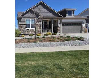 Charming two-story home featuring stone accents, a well-manicured lawn, and an attached two-car garage at 23579 E Swallow Cir, Aurora, CO 80016