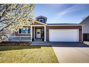 Charming home showcasing a two-car garage and well-maintained front yard with flower tree in full bloom at 2070 E 125Th Pl, Thornton, CO 80241