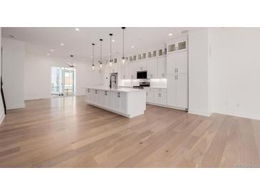 Bright, modern kitchen with large island, pendant lighting, and white cabinetry at 2361 Junegrass Ln, Louisville, CO 80027