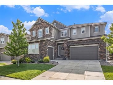 Charming two-story home featuring a stone facade, two-car garage, and manicured front yard under a bright sky at 1195 Fox Hills Ct, Erie, CO 80516
