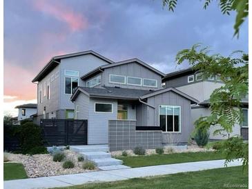Modern gray home featuring unique architecture, professional landscaping, and a charming walkway to the front door at 2339 W 66Th Ave, Denver, CO 80221