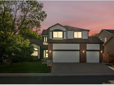 Two-story home featuring a three-car garage, white siding, and beautiful landscaping at sunset at 12695 Wolff St, Broomfield, CO 80020