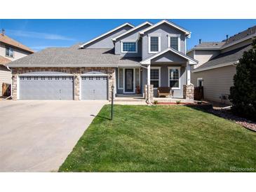 Charming two-story home featuring stone accents, a well-manicured lawn, and a spacious three-car garage at 7019 S Garrison St, Littleton, CO 80128