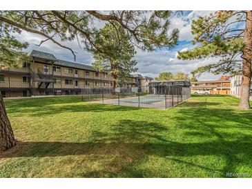 Community pool with lawn area and multifamily building in the background at 1723 Robb St # 44, Lakewood, CO 80215