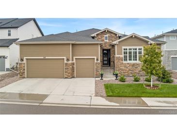 Charming home with a three-car garage, stone accents, landscaped yard, and inviting front entrance at 228 Rogers Ct, Castle Rock, CO 80104