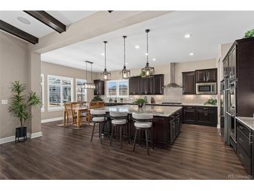 Spacious kitchen featuring dark wood cabinets, an oversized island, pendant lighting and a dining area at 228 Rogers Ct, Castle Rock, CO 80104