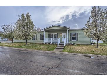 Charming single-story home features a welcoming front porch and well-maintained lawn with flowering trees at 7971 Larkspur Cir # 219, Frederick, CO 80530