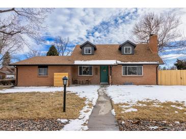 Charming brick home with a well-maintained lawn, complemented by a green door and dormer windows at 9962 W 77Th Ave, Arvada, CO 80005