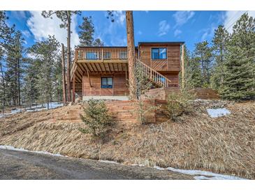 Charming wooden cabin with a spacious deck nestled in a serene, wooded setting at 7219 S Brook Forest Rd, Evergreen, CO 80439