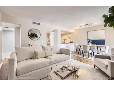 Bright living room boasts a comfortable sofa, stylish decor, and an open layout to the dining area at 14006 E Stanford Cir # K04, Aurora, CO 80015