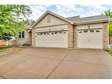 A home's exterior is defined by its brick accents and a two-car garage, with a concrete driveway at 5960 S Estes St, Littleton, CO 80123
