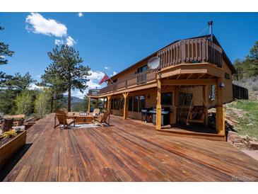 Expansive wooden deck with outdoor seating, grill, and scenic views of the surrounding landscape at 351 N Saddle Dr, Idaho Springs, CO 80452