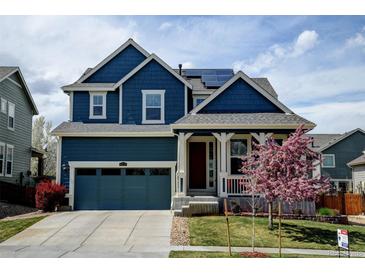Charming blue two-story home featuring a covered front porch, blue garage door, and a well-manicured lawn at 10733 Salida St, Commerce City, CO 80022
