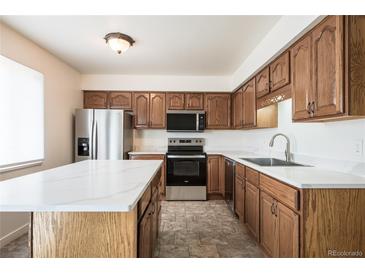 Bright kitchen features stainless appliances, white countertops, and light brown cabinets at 8627 Santa Fe Dr, Thornton, CO 80260