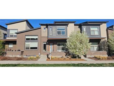 Contemporary townhome featuring a brick facade, modern windows, and beautifully landscaped front yard at 10066 Belvedere Cir, Lone Tree, CO 80124
