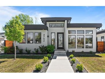 Modern home featuring a flat roof, a well-manicured lawn, and a concrete walkway leading to the front door at 4752 Eliot St, Denver, CO 80211